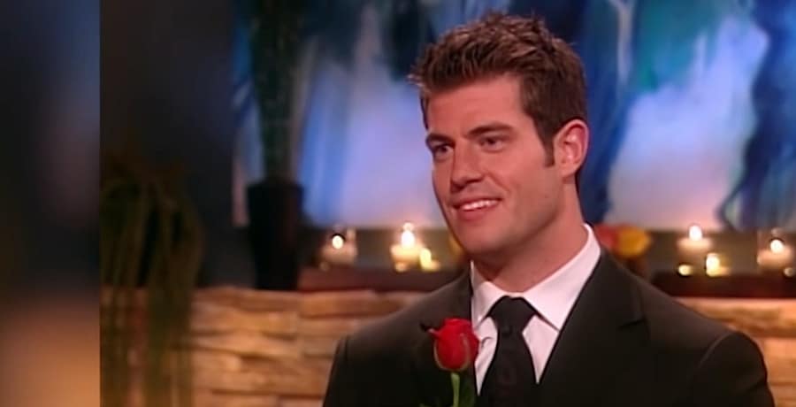 A man in a tux holds a red rose