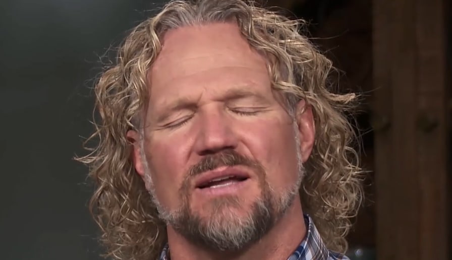 A man with curly blonde hair closes his eyes in anger