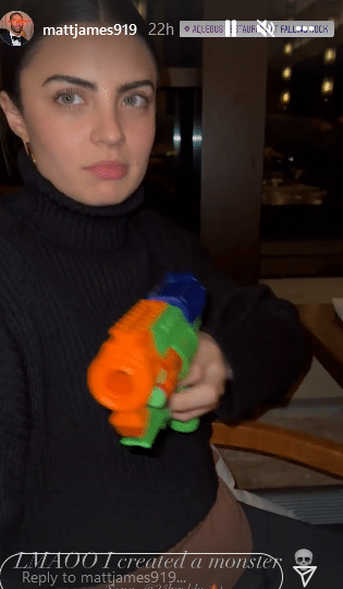 A woman points a nerf dart gun 