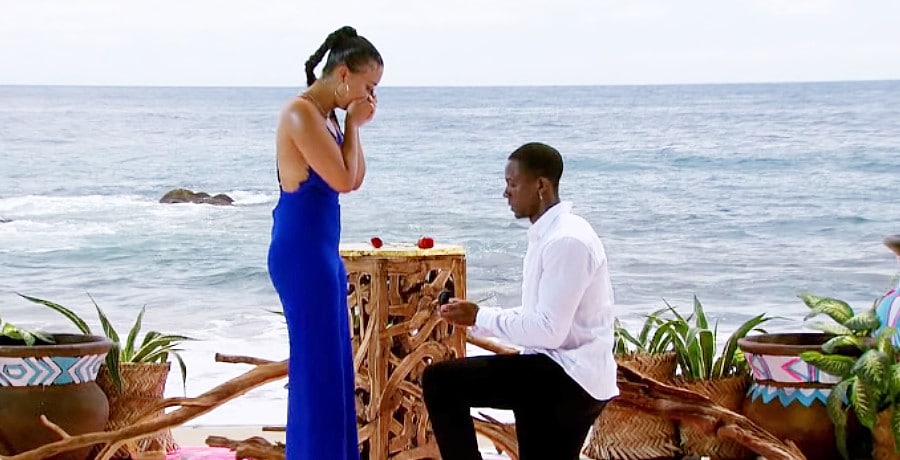 A man proposes to a woman in a blue dress
