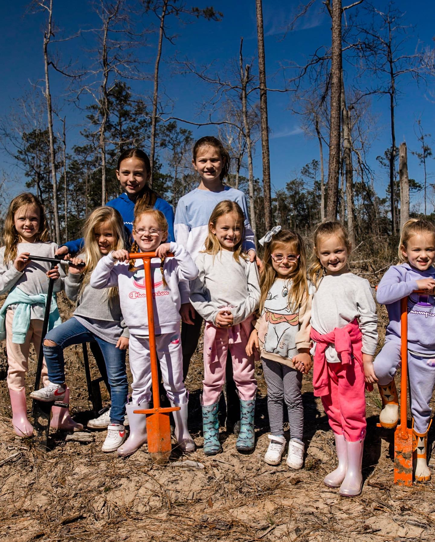 A man, woman, and children holding shovels