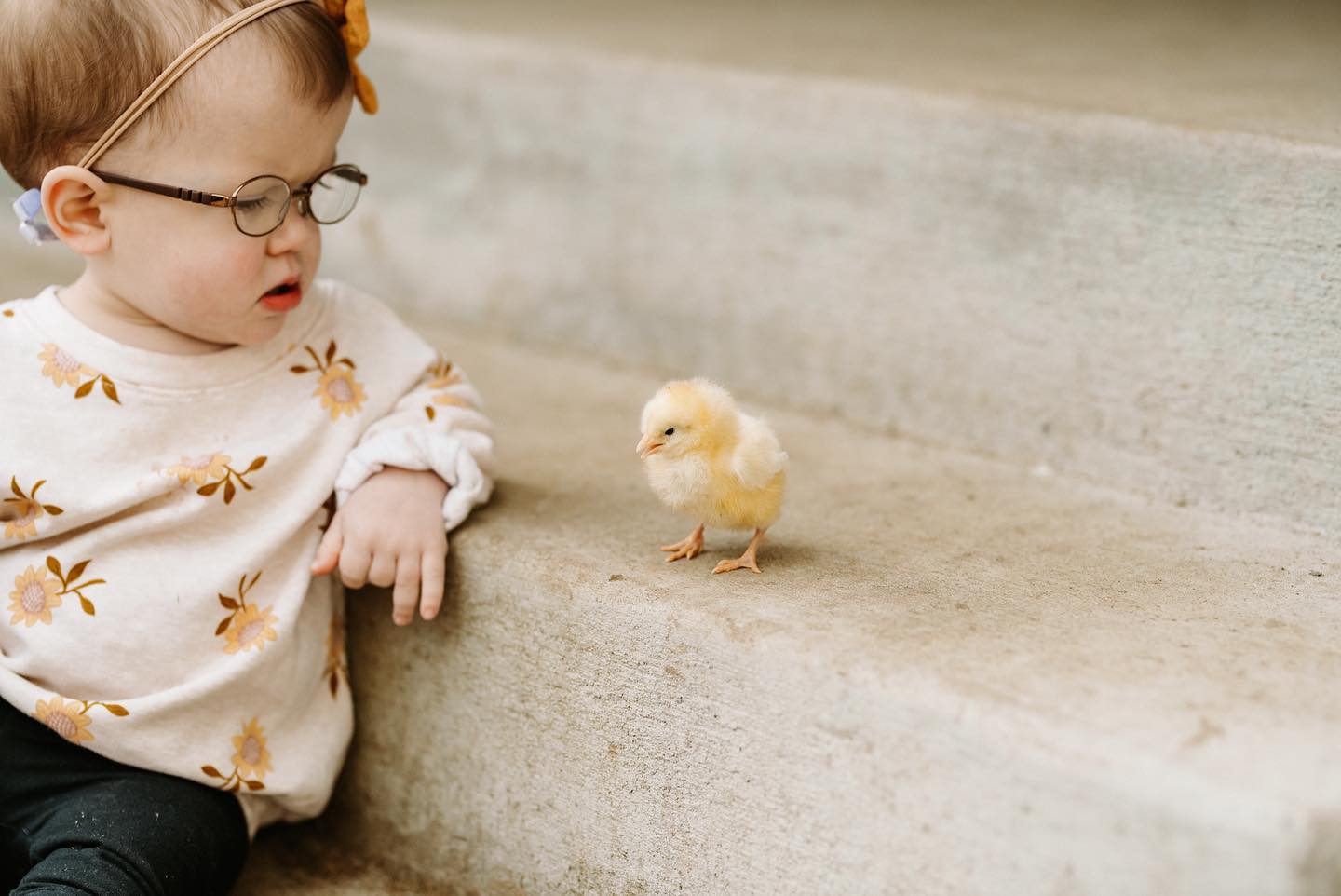A young girl sits next to a baby chicken