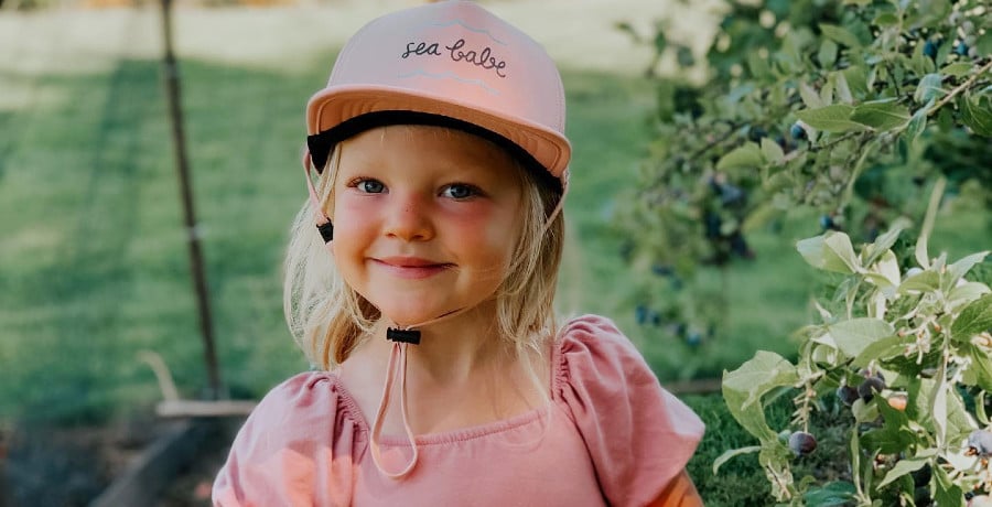 A young girl in a pink hat and pink shirt