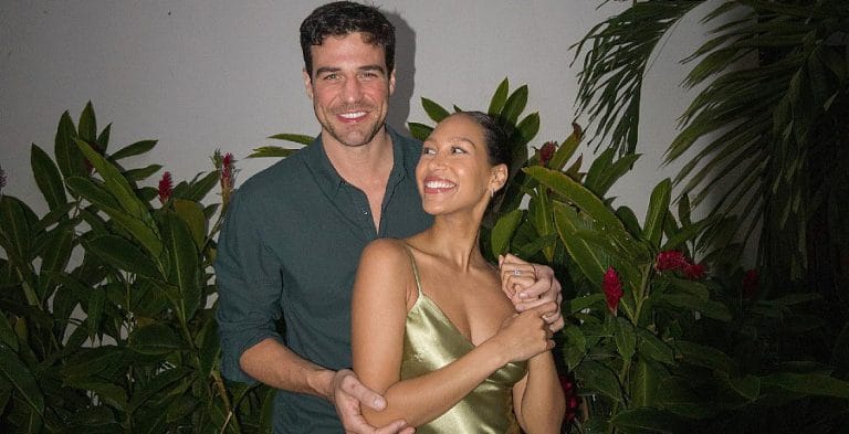 A man poses with a woman in a gold dress