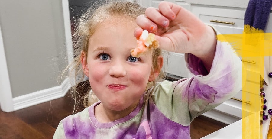 A young girl holding a piece of shrimp
