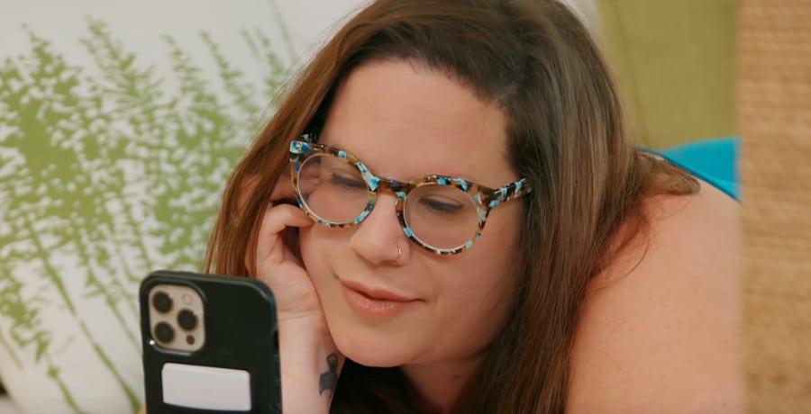 A woman in glasses looking at her phone 