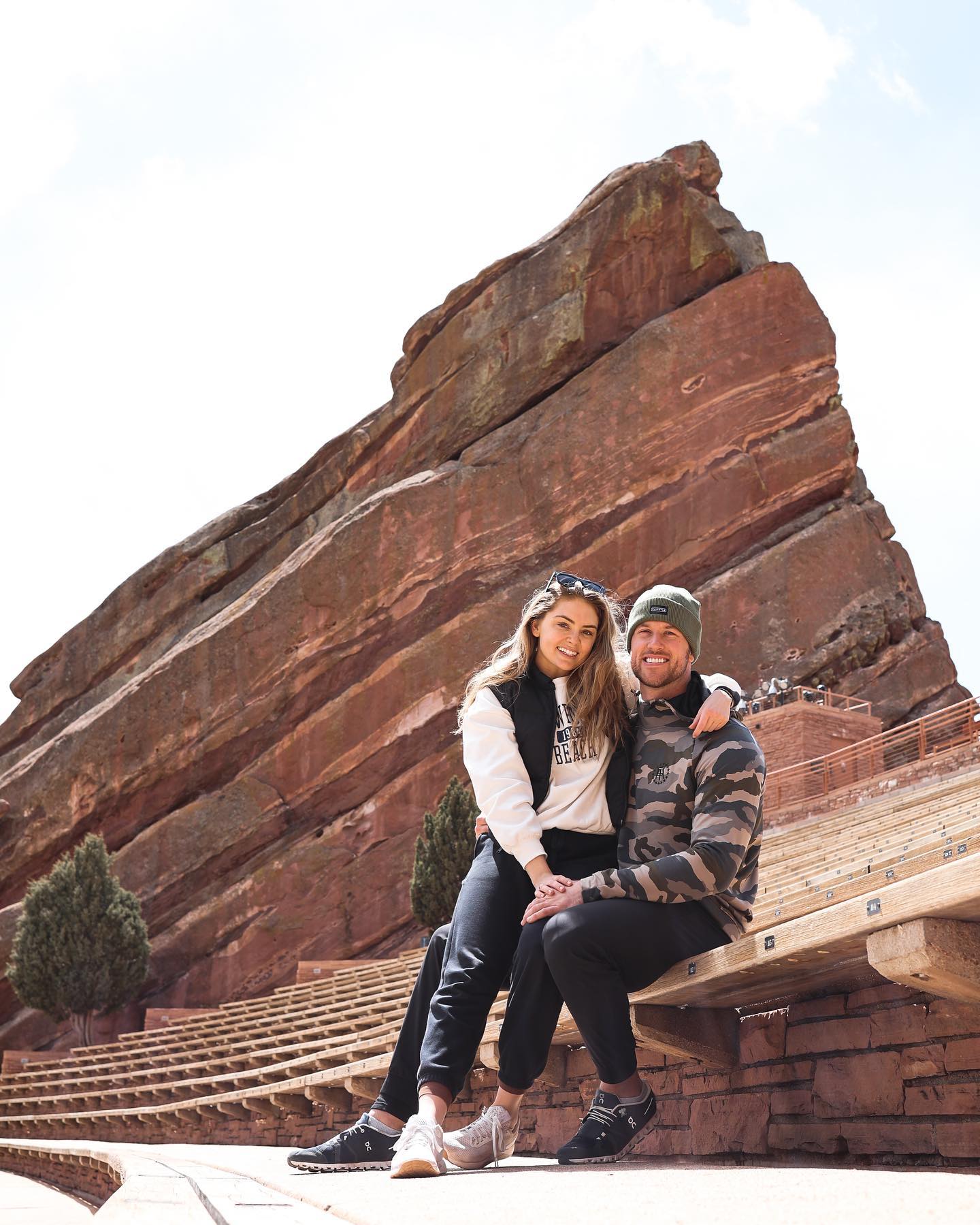 A man and a woman sitting on a large red rock