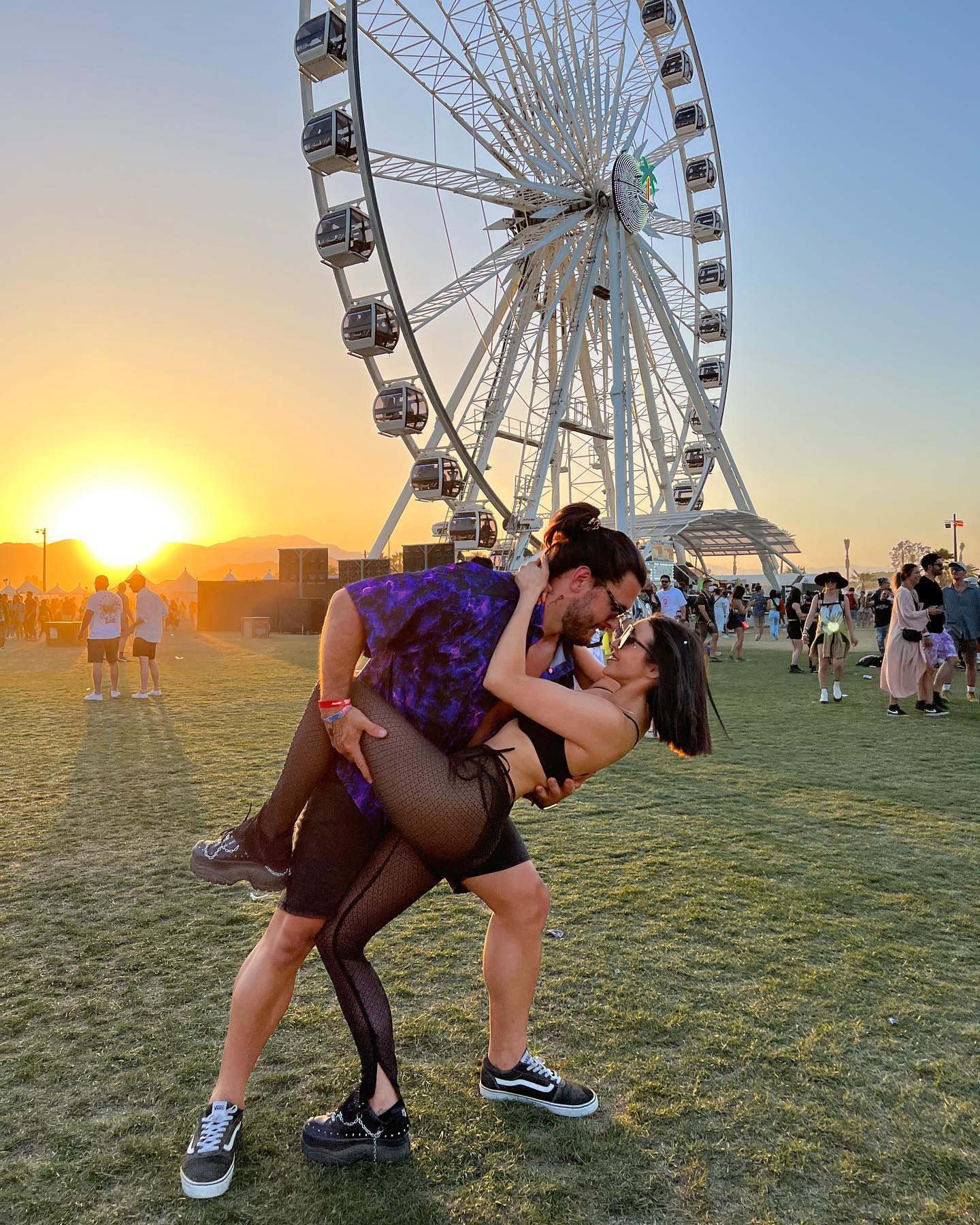 A man kissing a woman in front of a ferris wheel
