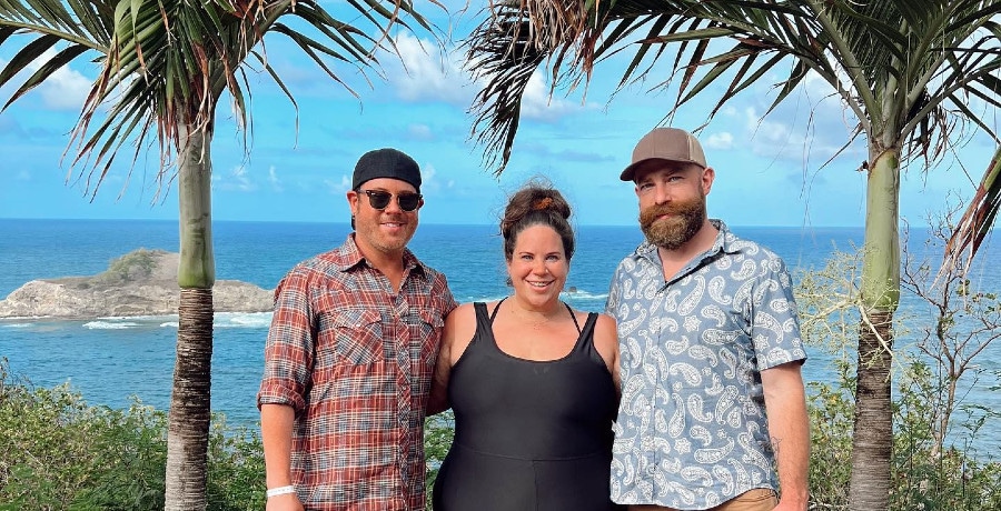 Two men and a woman pose on the beach