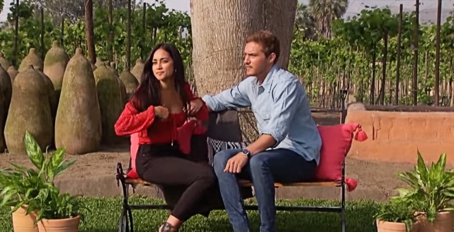 A woman in a red shirt and a man in a blue shrit sitting on a bench