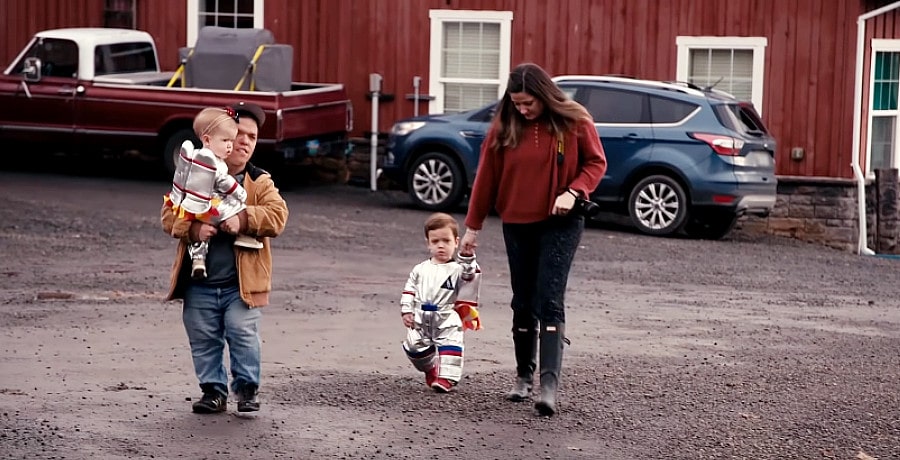 A man and a woman walk with their two young children 