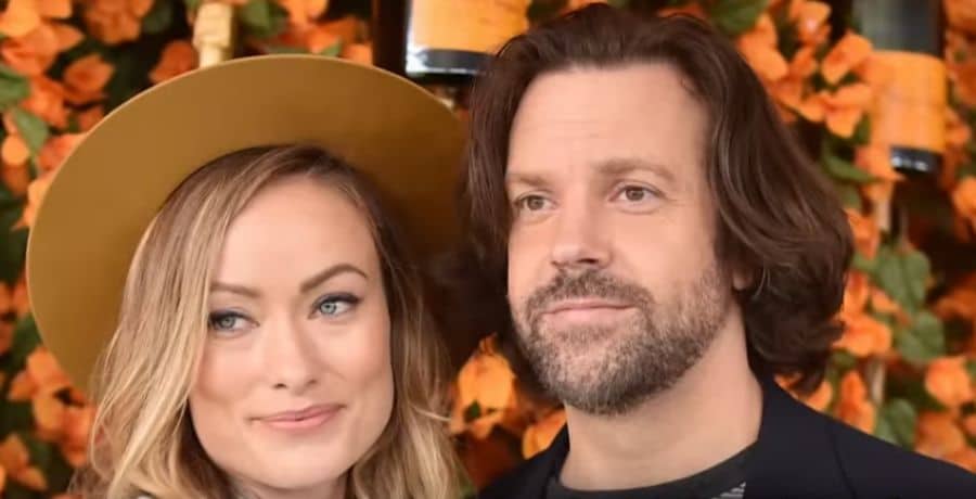 Olivia Wilde and Jason Sudeikis pose for a photo in front of autumn backdrop - Youtube/Entertainment Tonight