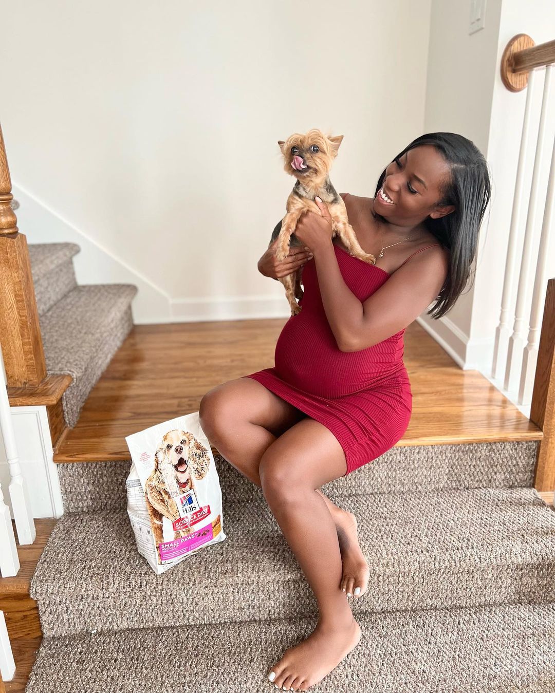 Briana Myles cuddles her dog on the staircase.