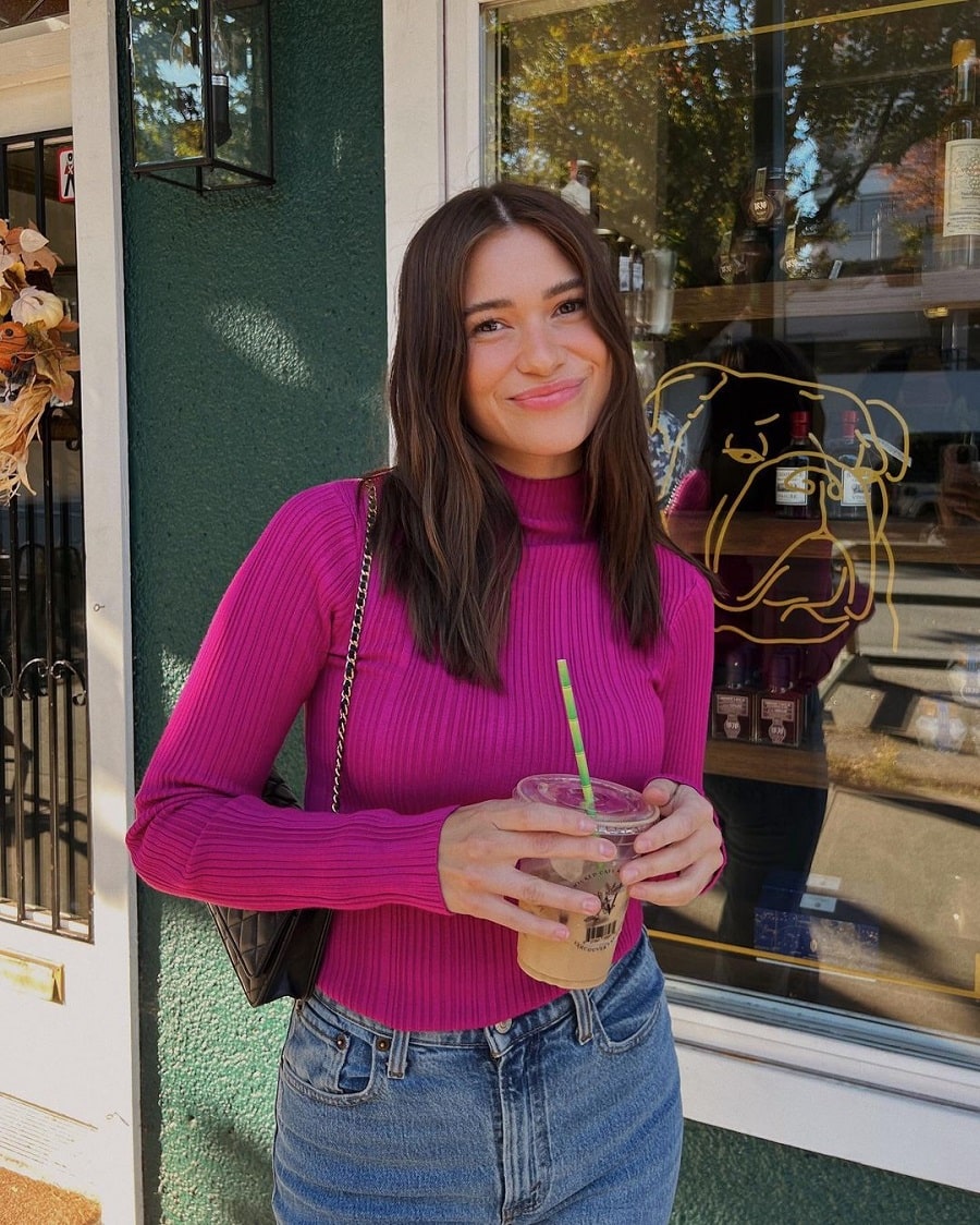 Mykenna Dorn grabs coffee in pink turtleneck sweater and jeans.