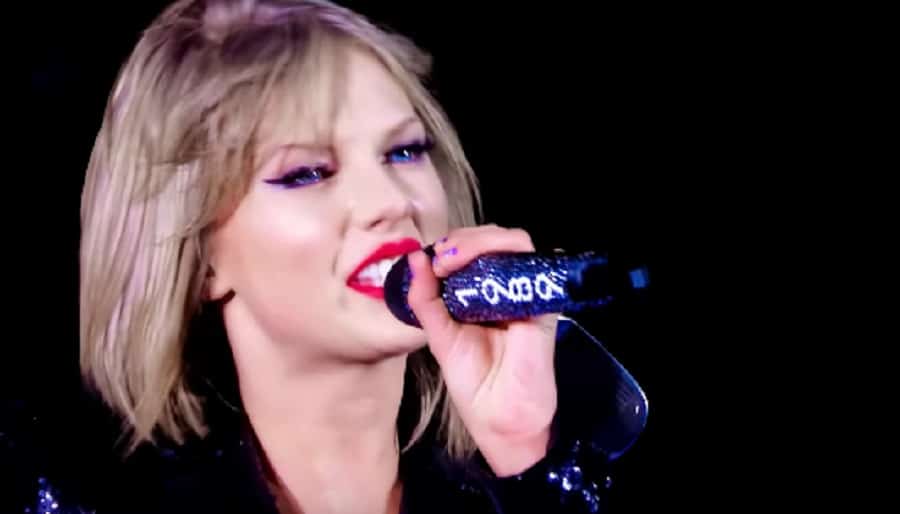 Taylor Swift Sings Into Microphone [Source: YouTube]