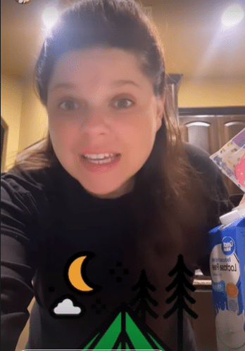 Amy Duggar King standing in kitchen wearing long sleeve black sweater with filter images covering her midsection.