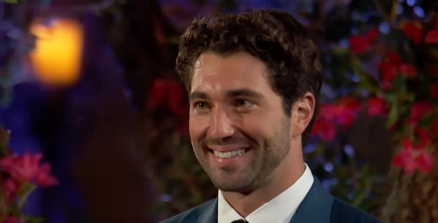 A man with short, curly brown hair in a blue suit and white shirt. 