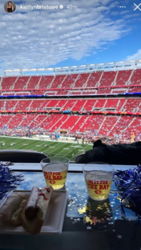 A photo of two beers on a shelf and a football field in the background