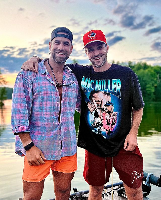 Two men standing in front of a lake.