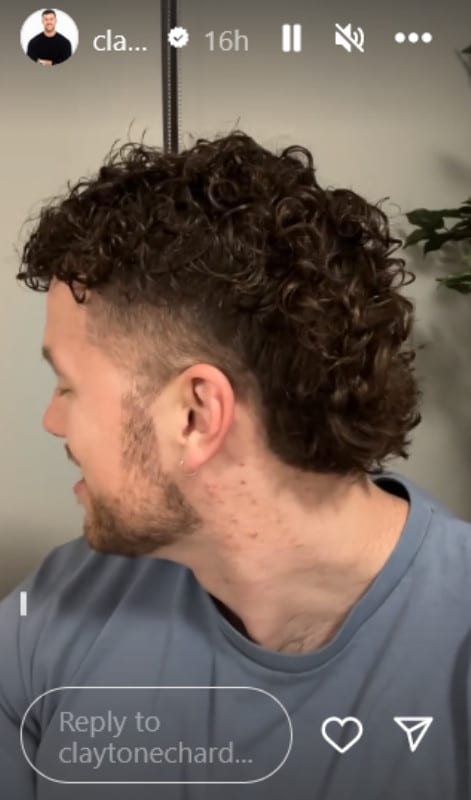 A man with his head turned showing off his curly brown hair.