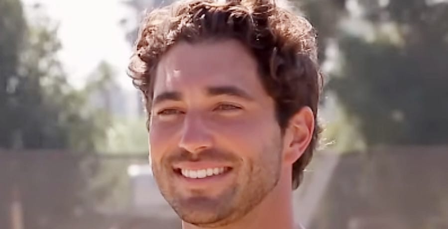 A man with curly brown hair smiling.