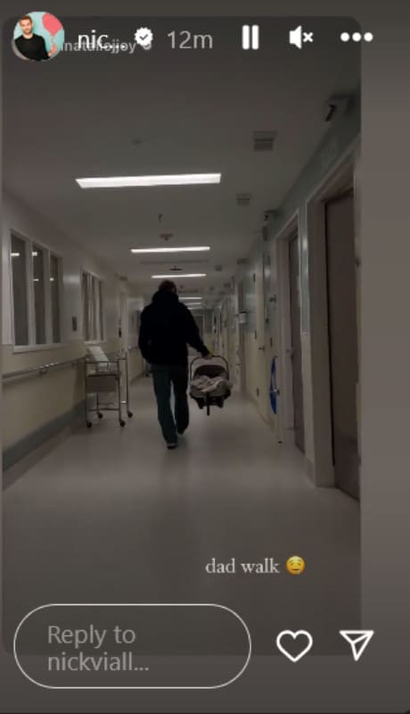 A photo of a man walking away carrying a baby carrier