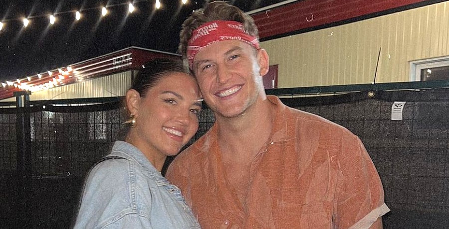 A man with a red bandana cuddling a woman with brown hair.
