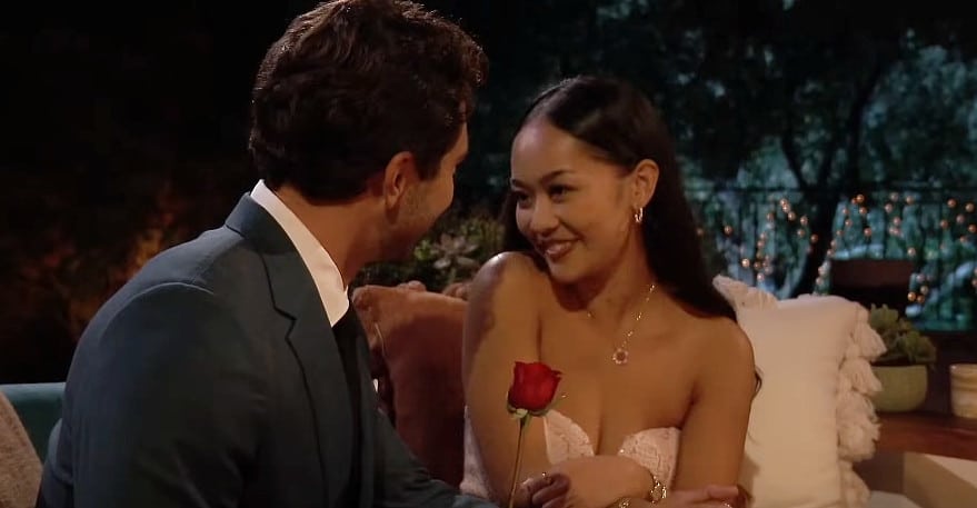 A man handing a woman a red rose.