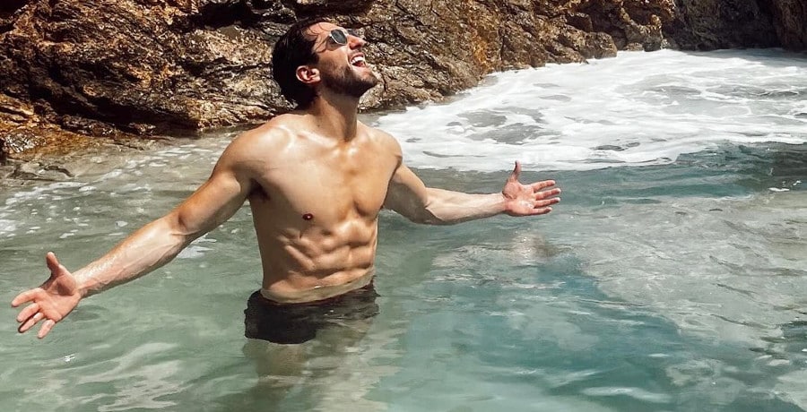 A man standing shirtless in a body of water