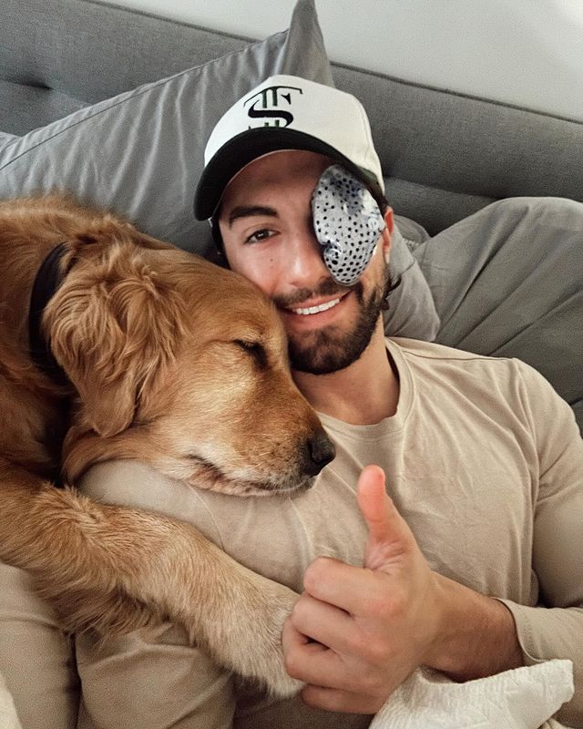A man with a patch over his eye cuddling with his dog