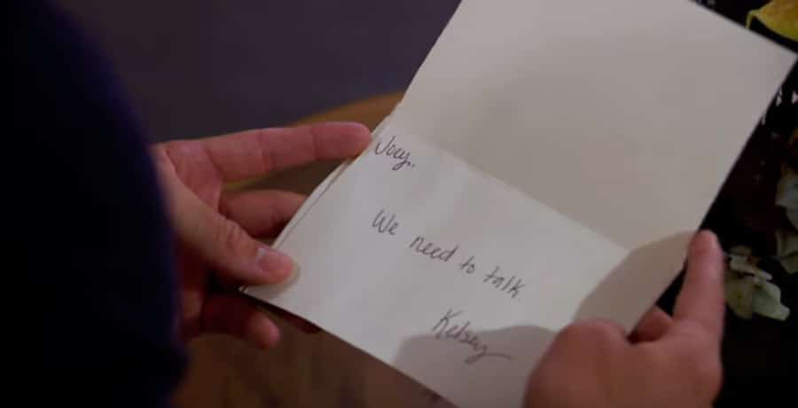 A man holding a letter that says "Joey, we need to talk, Kelsey."