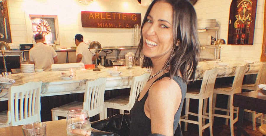 A woman with brown hair holding a glass of wine