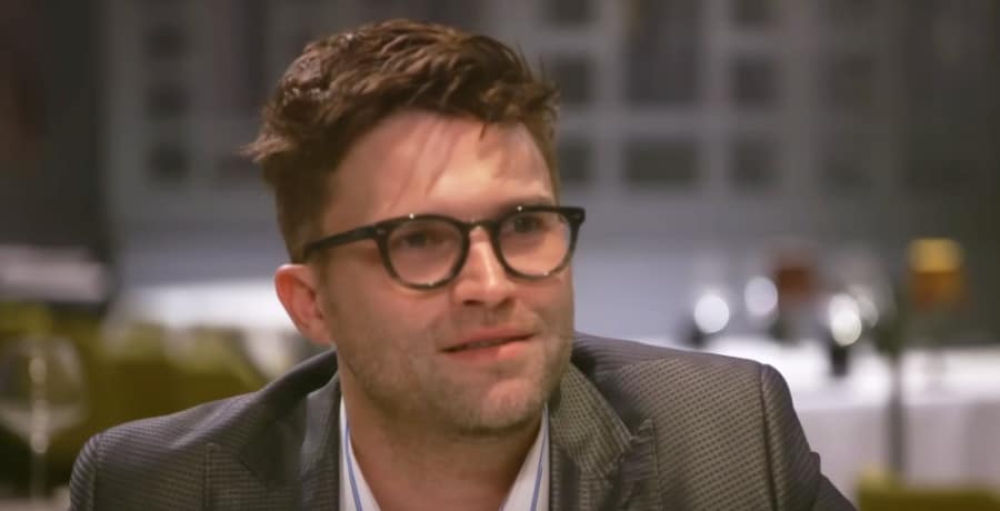 A man with brown hair wearing black glasses.