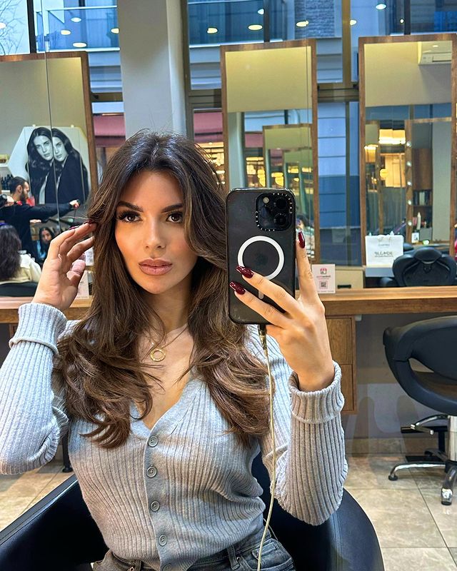 A woman with long brown hair taking a selfie.