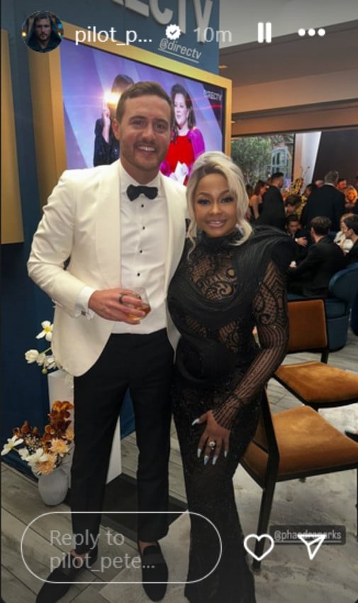 A man in a white suit posing with a Black woman in a black dress.